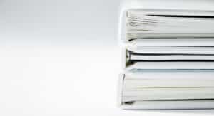 A tall stack of cardboard document folders holding filed paperwork