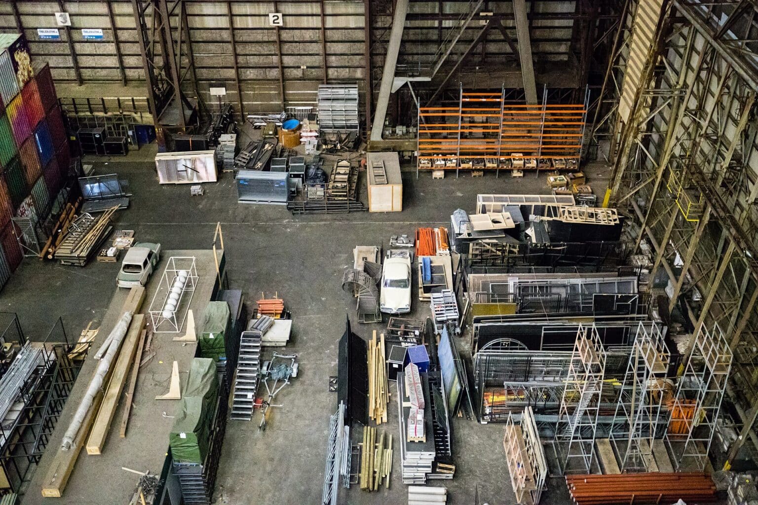 Overhead view of a large industrial storage hall filled with mixed pallets, racking, timber and steel