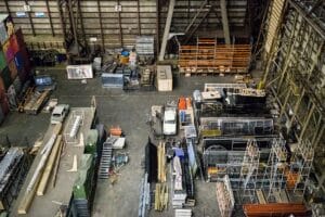 Overhead view of a large industrial storage hall filled with mixed pallets, racking, timber and steel