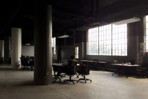 One person working alone at a laptop in a large, mostly empty open-plan office