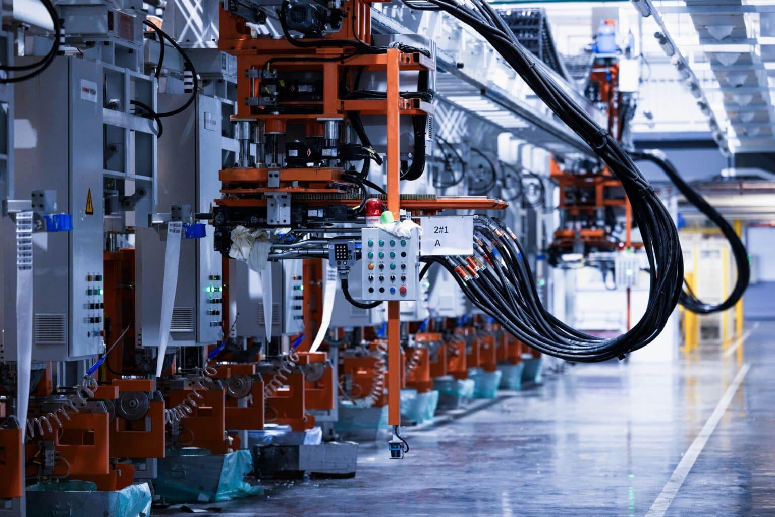 A line of electrical control equipment running along a factory floor